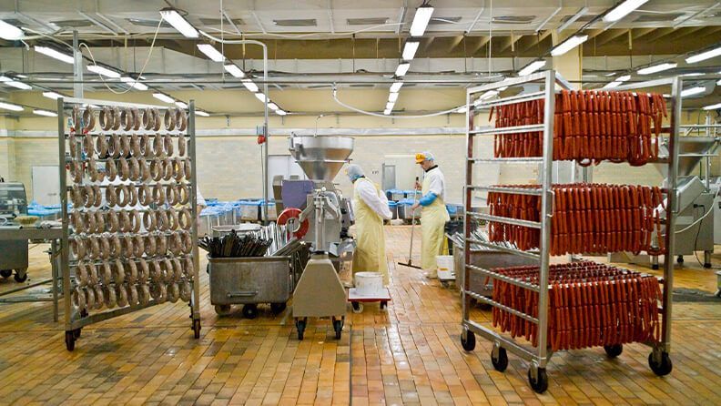 Personas trabajando en una fábrica de productos cárnicos