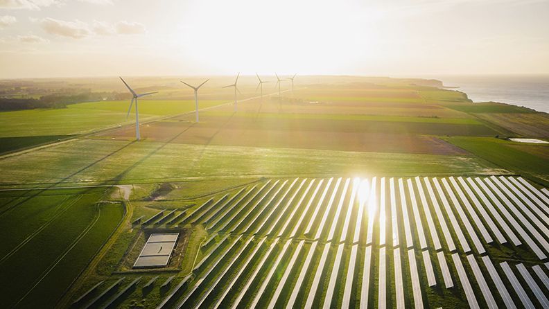 Granja de turbinas eólicas y paneles solares en un campo para producir energía verde renovable